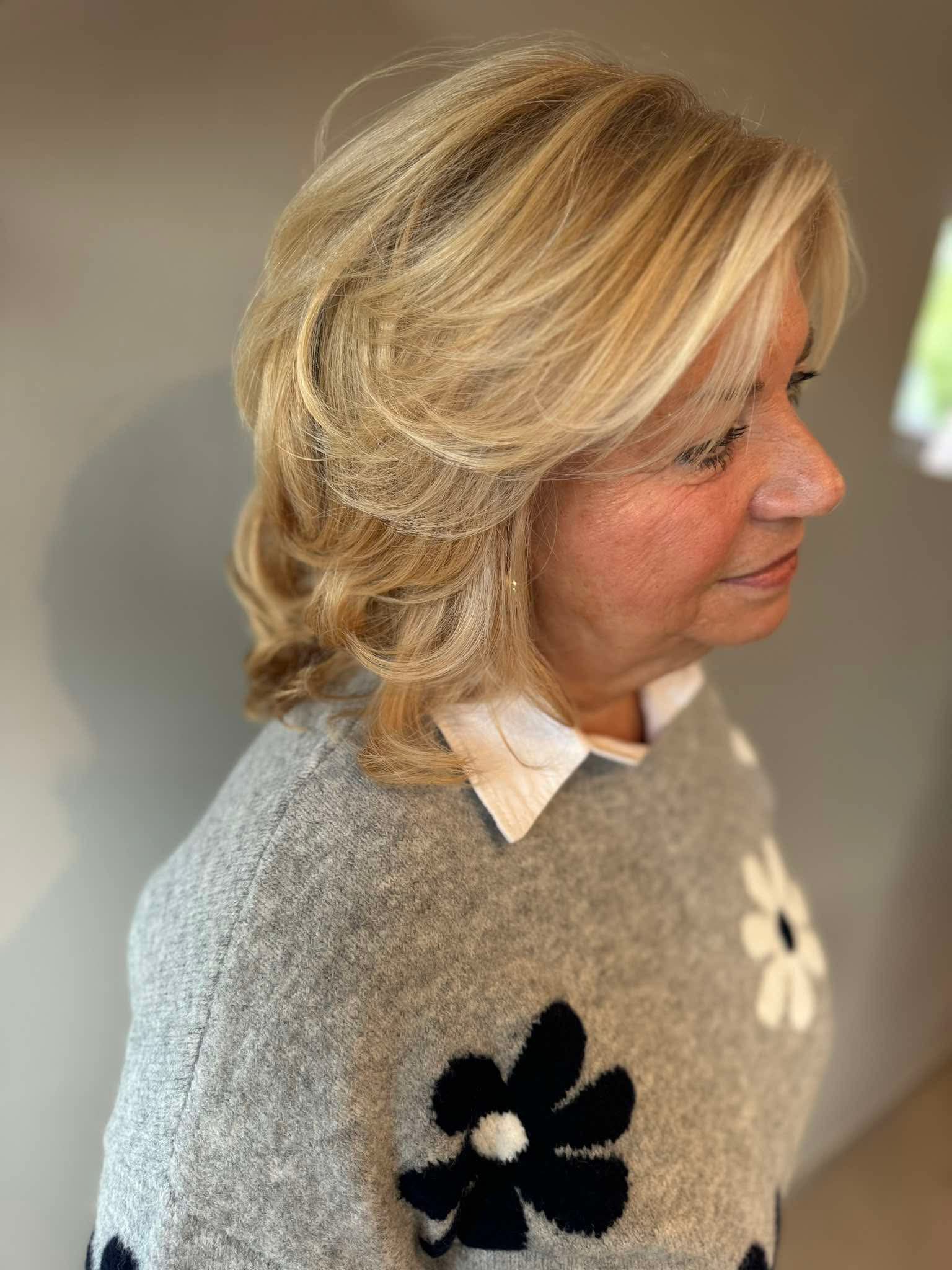 Dame met geblondeerd haar waarbij lokken omhoog gehouden worden om snit te tonen in detail.