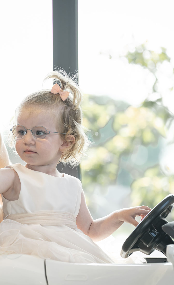 Klein meisje met bril die in de kapperswagen zit die bedoeld is om de knipervaring van kinderen aangenamer te maken.
